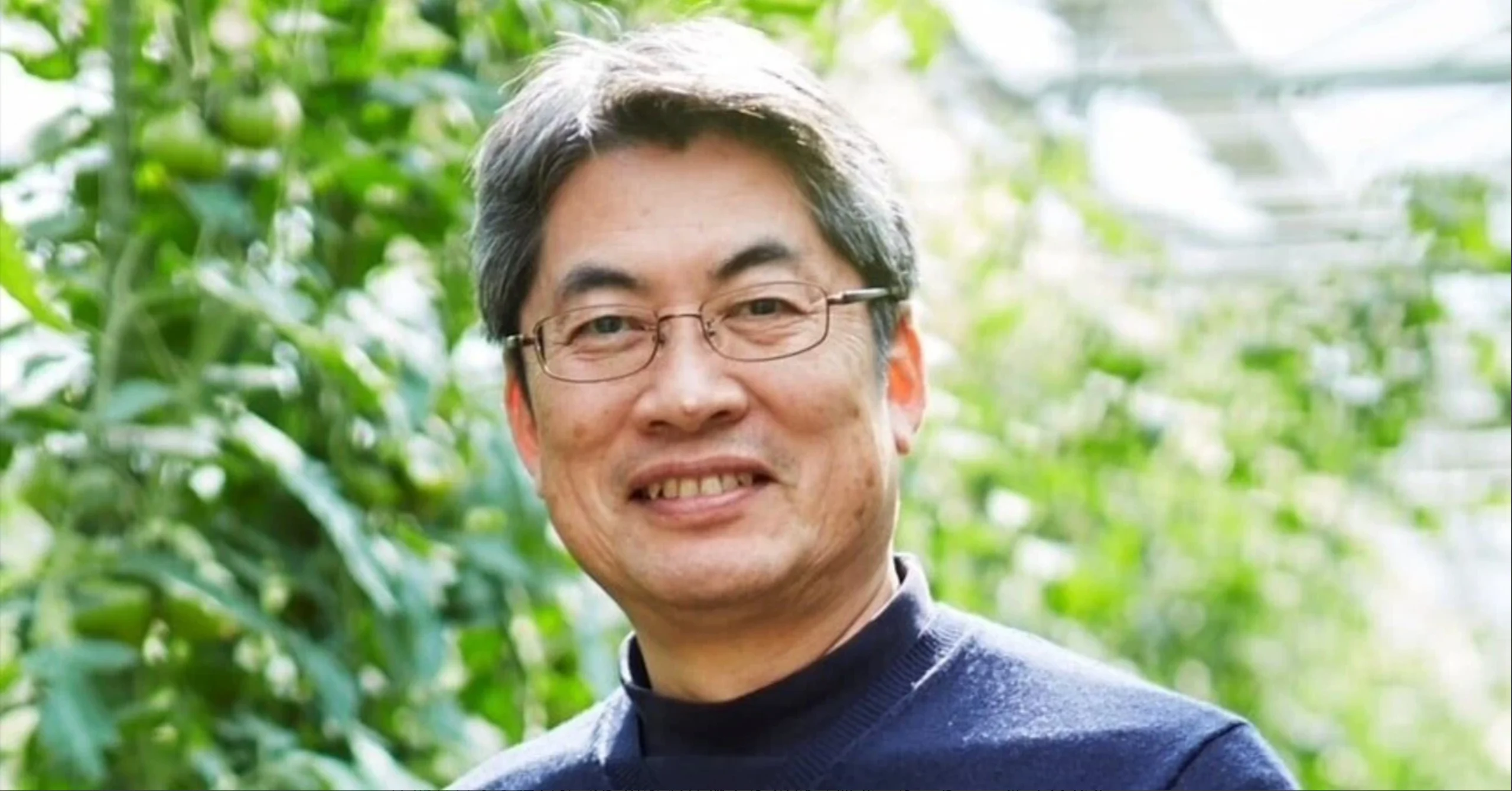 温室を背景にほほ笑むルートレック・ネットワークス代表取締役社長の佐々木伸一さん